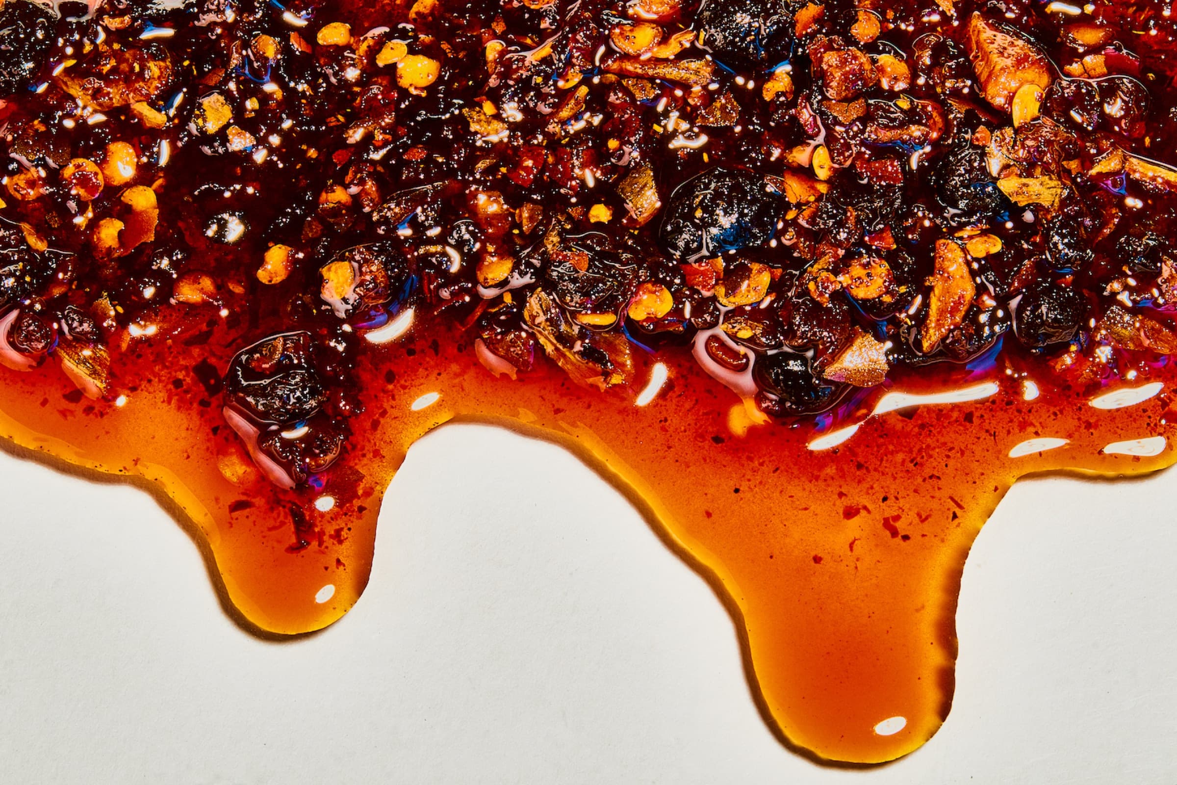 Macro view of Sichuan chili crisp showing oil, chile, fermented beans, and crisp solids