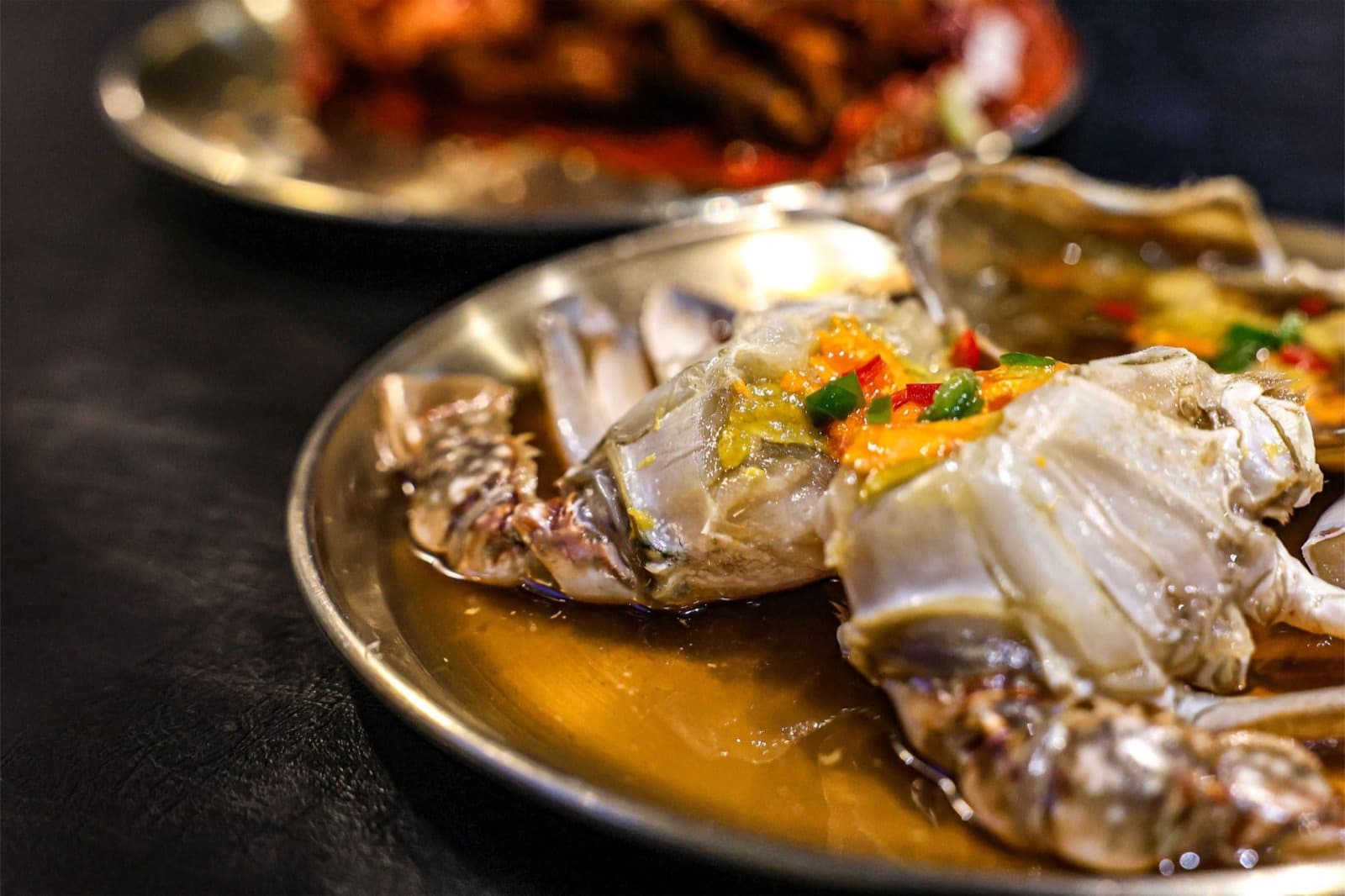 Bowl of ganjang gejang soy-marinated crab topped with orange crab roe and sesame