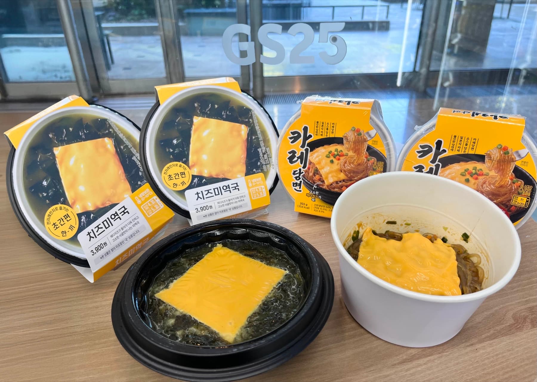 GS25 cheese miyeokguk and curry dangmyeon packs with prepared bowls topped by yellow cheese slices