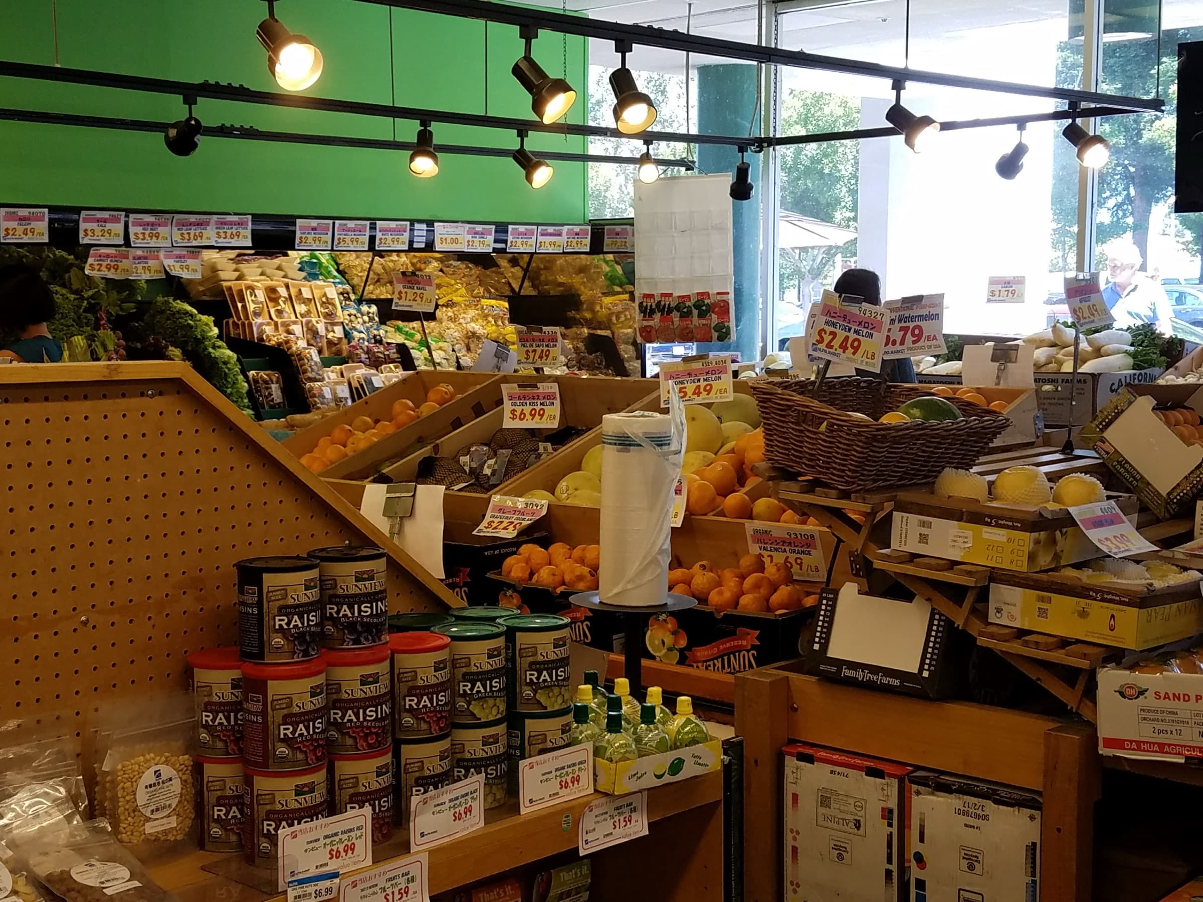 Asian supermarket produce section with melons, daikon, and warm track lighting