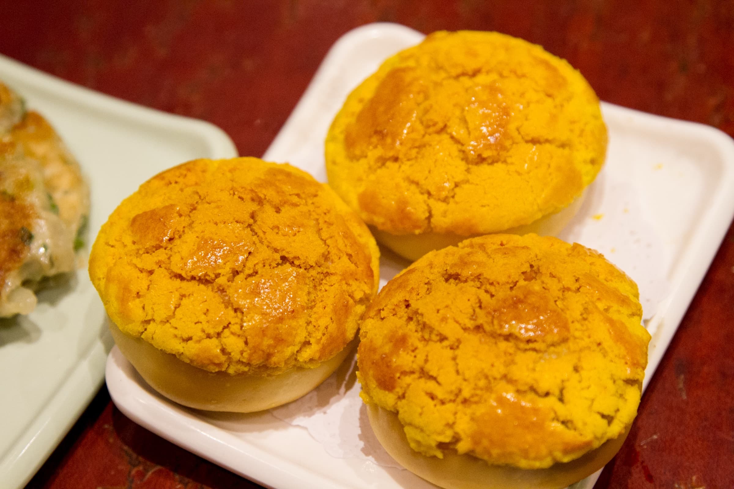 Golden pineapple buns on a white plate, warm bakery light
