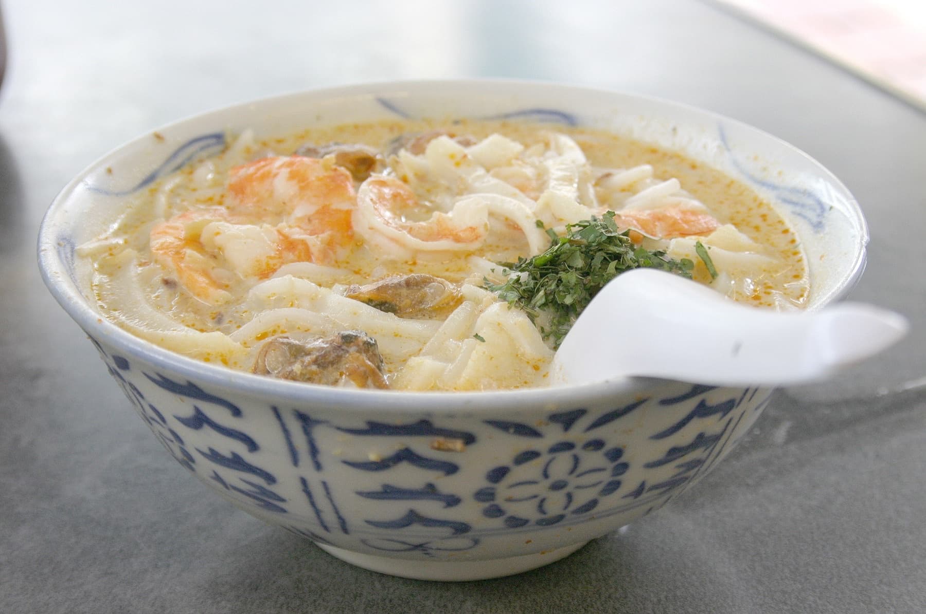 Bowl of Katong-style Singapore laksa with prawns in a blue-patterned ceramic bowl
