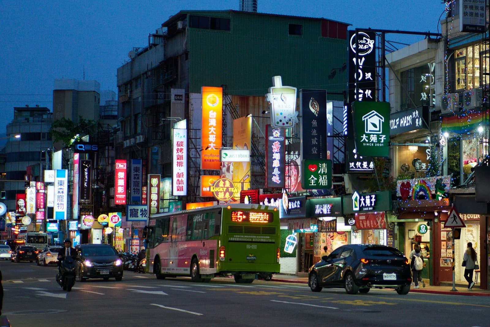 Busy Taipei commercial street with neon shop signs at dusk