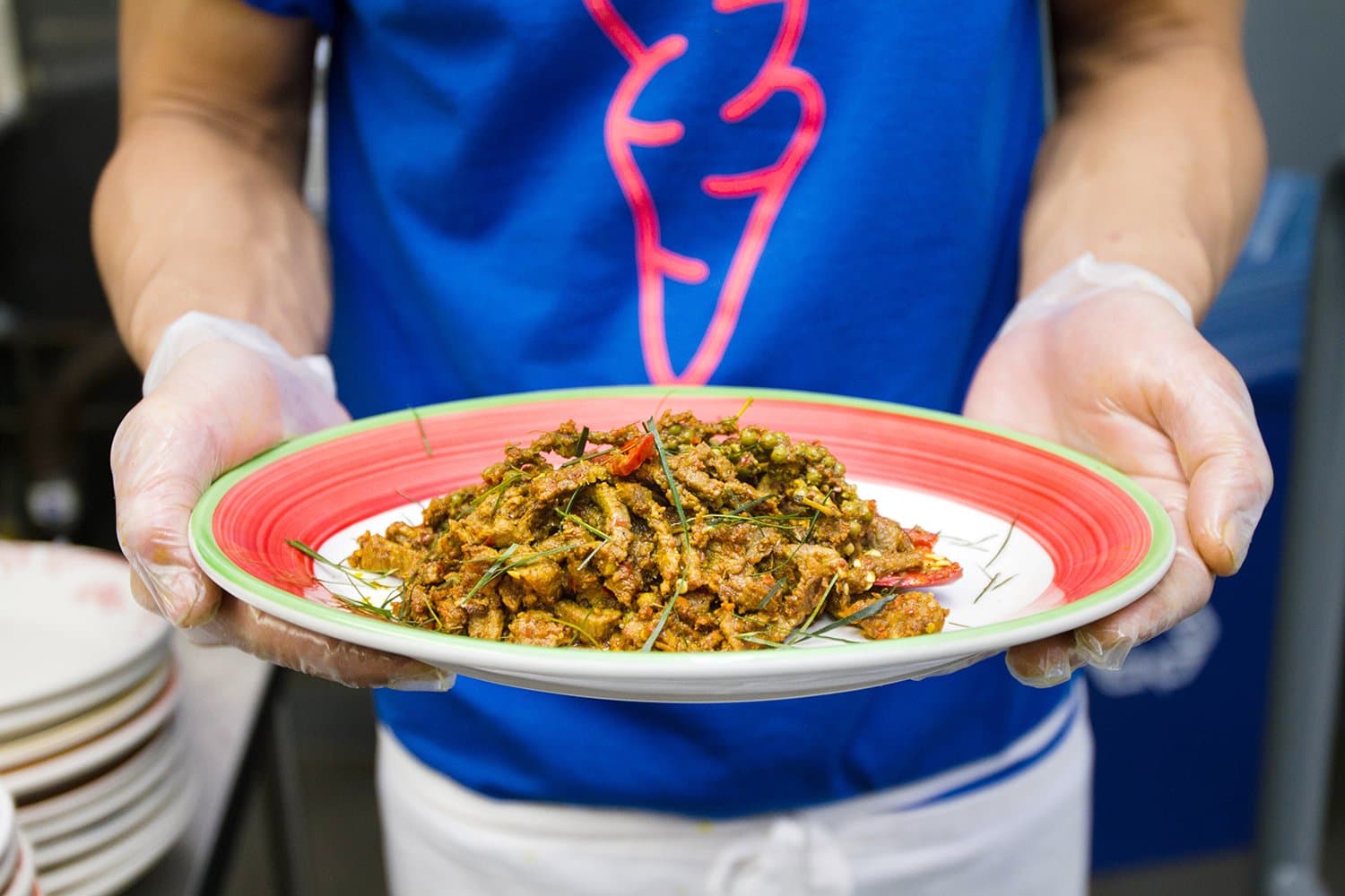 Chef Sirichai Sreparplarn holding a plate of kua kling, a dry curried beef dish, at the original Ugly Baby in 2017